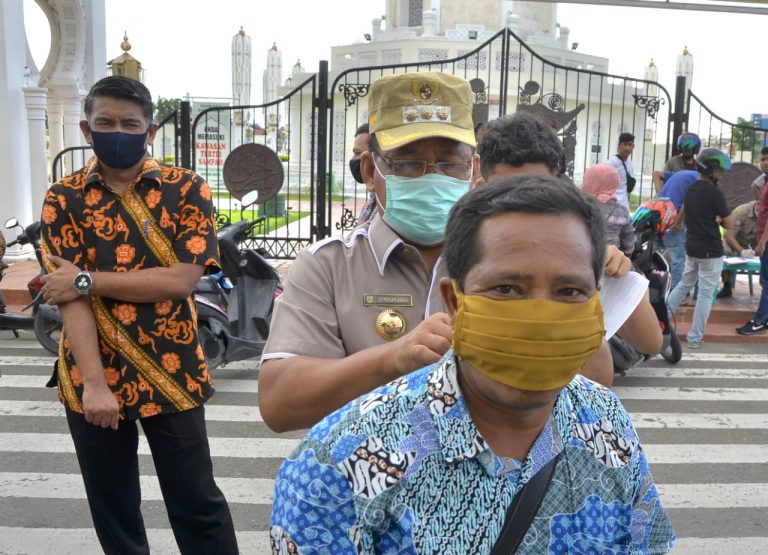 Wali Kota Banda Aceh Aminullah Usman Memasang Masker Ke Warga Yang Melintas Saat Memimpin Razia Masker Di Jalan Depan Masjid Raya Baiturrahman, Kamis