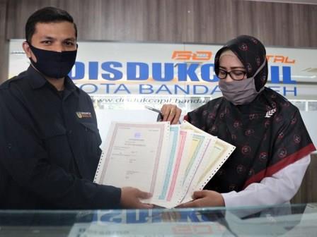 Kadis Disdukcapil Banda Aceh, Dra. Emila Sovayana (kanan) dan staf pelayanan (kiri) memperlihatkan blanko dokumen kependudukan