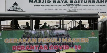 Prajurit Kodam IM membagikan masker kepada pengguna jalan di depan Masjid Raya Baiturrahman Banda Aceh yang dijahit langsung di lokasi, Selasa (29/9)