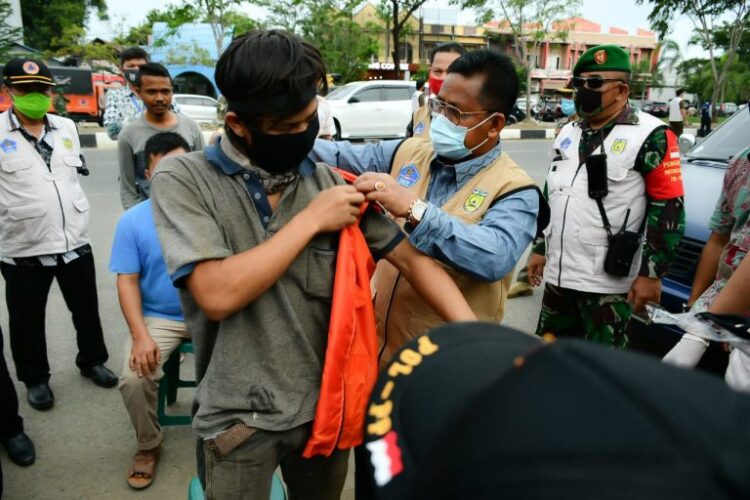 Wali Kota Banda Aceh, Aminullah Usman memakaikan rompi penyapu jalan kepada seorang warga pelanggar protokol kesehatan yang tidak memakai masker saat razia di Jalan Prof Ali Hasjmy kawasan Pango Raya, Kamis (22/10)