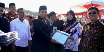 Pj Bupati Aceh Besar Muhammad Iswanto menyerahkan penghargaan kepada guru pada upacara peringatan HGN dan HUT ke-77 PGRI di Lapangan Angkasa Pura, Blang Bintang, Sabtu (26/11)