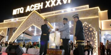 Pj Gubernur Aceh Achmad Marzuki menerima Piala Bergilir MTQ Aceh dari Pj Bupati Aceh Besar Muhammad Iswanto, selaku Juara Umum pada MTQ XXXV, pada pembukaan MTQ XXXVI Aceh, di Lapangan Pendopo Bupati Simeulue, Ahad malam (26/11)