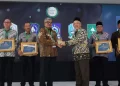 Plt Direktur Eksekutif KNEKS Taufik Hidayat menyerahkan penghargaan kepada Pj Gubernur Aceh Bustami Hamzah, di Menara Syariah, Pantai Indah Kapuk 2, Tangerang, Banten, Senin (20/5). (Foto: Humas BPPA)