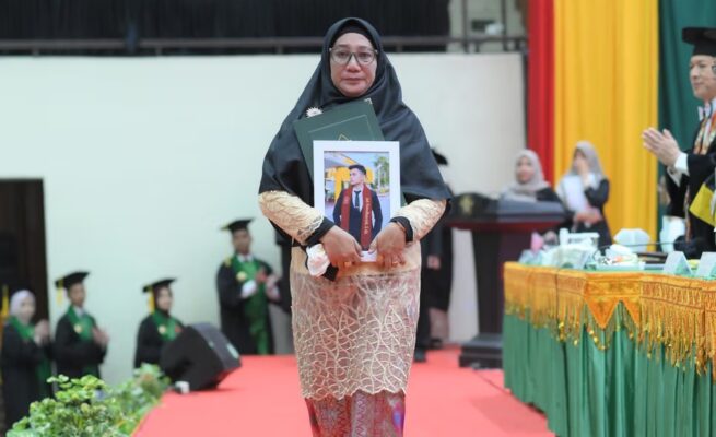 Fitri Ermawati, ibu dari almarhum Jodi Ramadhansyah menerima ijazah pada wisuda Angkatan ke-165 USK di Gedung AAC Dayan Dawood, Rabu (28/5/2025). (Foto: Dok. USK Banda Aceh)