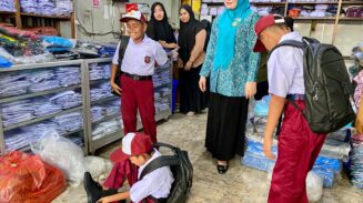 Marlina Usman, Bunda PAUD Aceh, membantu memilihkan sepatu dan seragam baru untuk 3 siswa SD di Blangpidie, Selasa (17/6). Aksi spontan ini dilakukan setelah ia melihat sepatu lusuh yang mereka kenakan. (Foto: For Infoaceh.net)