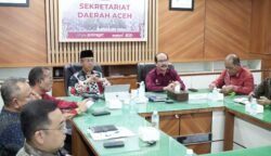 Kakanwil Kemenkumham Aceh Meurah Budiman, menyampaikan laporan capaian pengesahan badan hukum Koperasi Merah Putih Desa/Kelurahan dalam rapat evaluasi di Ruang Setda Aceh, Kamis (26/6/2025). (Foto: Ist)