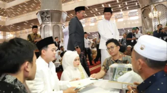 Infoaceh.net – Sebanyak 100 pasangan mengikuti prosesi nikah massal yang digelar di Masjid Istiqlal, Jakarta, Sabtu (28/6/2025). Acara ini menjadi bagian dari peringatan Tahun Baru Islam 1 Muharram 1447 Hijriah yang diselenggarakan oleh Kementerian Agama RI. Pantauan di lokasi, ratusan mempelai pria dan wanita tampak khidmat mengenakan busana adat dan pakaian muslim formal. Mereka duduk berdampingan di atas karpet merah masjid, didampingi wali serta keluarga masing-masing. Di depan mereka tertata kotak mahar dan dokumen nikah yang menjadi simbol keabsahan prosesi akad. Akad nikah berlangsung bergantian di bawah pengawasan para penghulu dari Kantor Urusan Agama (KUA). Prosesi berjalan tertib dan penuh haru. Menteri Agama Nasaruddin Umar yang hadir langsung menyampaikan apresiasinya terhadap antusiasme para peserta. Ia menyebut nikah massal ini bukan sekadar peristiwa administratif, melainkan momentum spiritual yang membawa berkah. “Insyaallah ini momen penuh berkah. Fasilitas sudah kami siapkan, termasuk kamar hotel untuk semua pasangan. Malam ini, silakan menikmati malam halal,” ujar Nasaruddin yang disambut gelak tawa para hadirin. Tak hanya akomodasi, beberapa pasangan juga mendapatkan bantuan modal usaha dari mitra penyelenggara. Nasaruddin berharap pernikahan massal ini menjadi awal kehidupan yang sakinah, baik di dunia maupun akhirat. “Pernikahan bukan hanya tanggung jawab duniawi, tapi juga hingga akhirat. Ibu-ibu, jangan takut disaingi bidadari surga, karena ibu-ibu yang salehah akan lebih cantik dari bidadari,” tambahnya dengan senyum. Program nikah massal ini ditujukan bagi masyarakat kurang mampu yang terkendala biaya. Pendaftaran dilakukan melalui KUA masing-masing hingga 20 Juni 2025. Seluruh fasilitas diberikan secara gratis, termasuk bimbingan perkawinan (Bimwin), buku nikah, serta suvenir resmi dari panitia. Direktur Jenderal Bimbingan Masyarakat Islam Kemenag, Abu Rokhmad, menegaskan bahwa program ini bertujuan memberikan legalitas pernikahan baik secara agama maupun negara. “Kami ingin membuka akses pernikahan yang sah tanpa beban biaya, agar masyarakat bisa melangsungkan kehidupan rumah tangga dengan tenang dan resmi,” ujarnya. Suasana hangat, tawa haru, dan rasa syukur mewarnai seluruh rangkaian acara, menjadikan nikah massal ini sebagai salah satu peringatan Tahun Baru Islam yang paling membekas di hati para peserta dan keluarga.