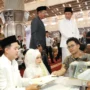 Infoaceh.net – Sebanyak 100 pasangan mengikuti prosesi nikah massal yang digelar di Masjid Istiqlal, Jakarta, Sabtu (28/6/2025). Acara ini menjadi bagian dari peringatan Tahun Baru Islam 1 Muharram 1447 Hijriah yang diselenggarakan oleh Kementerian Agama RI. Pantauan di lokasi, ratusan mempelai pria dan wanita tampak khidmat mengenakan busana adat dan pakaian muslim formal. Mereka duduk berdampingan di atas karpet merah masjid, didampingi wali serta keluarga masing-masing. Di depan mereka tertata kotak mahar dan dokumen nikah yang menjadi simbol keabsahan prosesi akad. Akad nikah berlangsung bergantian di bawah pengawasan para penghulu dari Kantor Urusan Agama (KUA). Prosesi berjalan tertib dan penuh haru. Menteri Agama Nasaruddin Umar yang hadir langsung menyampaikan apresiasinya terhadap antusiasme para peserta. Ia menyebut nikah massal ini bukan sekadar peristiwa administratif, melainkan momentum spiritual yang membawa berkah. “Insyaallah ini momen penuh berkah. Fasilitas sudah kami siapkan, termasuk kamar hotel untuk semua pasangan. Malam ini, silakan menikmati malam halal,” ujar Nasaruddin yang disambut gelak tawa para hadirin. Tak hanya akomodasi, beberapa pasangan juga mendapatkan bantuan modal usaha dari mitra penyelenggara. Nasaruddin berharap pernikahan massal ini menjadi awal kehidupan yang sakinah, baik di dunia maupun akhirat. “Pernikahan bukan hanya tanggung jawab duniawi, tapi juga hingga akhirat. Ibu-ibu, jangan takut disaingi bidadari surga, karena ibu-ibu yang salehah akan lebih cantik dari bidadari,” tambahnya dengan senyum. Program nikah massal ini ditujukan bagi masyarakat kurang mampu yang terkendala biaya. Pendaftaran dilakukan melalui KUA masing-masing hingga 20 Juni 2025. Seluruh fasilitas diberikan secara gratis, termasuk bimbingan perkawinan (Bimwin), buku nikah, serta suvenir resmi dari panitia. Direktur Jenderal Bimbingan Masyarakat Islam Kemenag, Abu Rokhmad, menegaskan bahwa program ini bertujuan memberikan legalitas pernikahan baik secara agama maupun negara. “Kami ingin membuka akses pernikahan yang sah tanpa beban biaya, agar masyarakat bisa melangsungkan kehidupan rumah tangga dengan tenang dan resmi,” ujarnya. Suasana hangat, tawa haru, dan rasa syukur mewarnai seluruh rangkaian acara, menjadikan nikah massal ini sebagai salah satu peringatan Tahun Baru Islam yang paling membekas di hati para peserta dan keluarga.