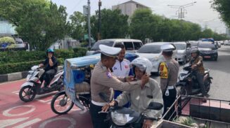 Satlantas Polresta Banda Aceh membagikan puluhan helm secara gratis kepada pengendara sepeda motor, Senin (21/7). (Foto: Ist)