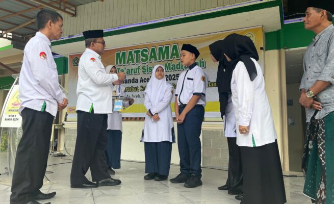 Kakanwil Kemenag Aceh Azhari didampingi Kepala MTsN 1 Banda Aceh Hj Ummiyani SAg MPd dan ketua komite menyematkan tanda peserta kepada dua perwakilan siswa, Senin, 14 Juli 2025. (Foto: Ist)
